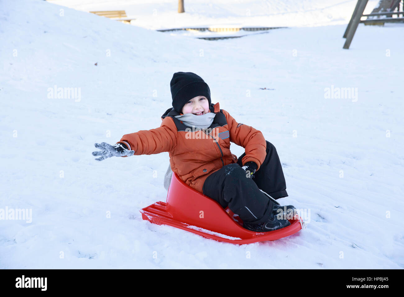 Kind junge spielen und Lachen auf verschneiten Winterspaziergang in der Natur. Frost Wintersaison. Niedlicher kleine Junge mit Untertasse Schlitten im Freien auf Wintertag, Talfahrt Stockfoto