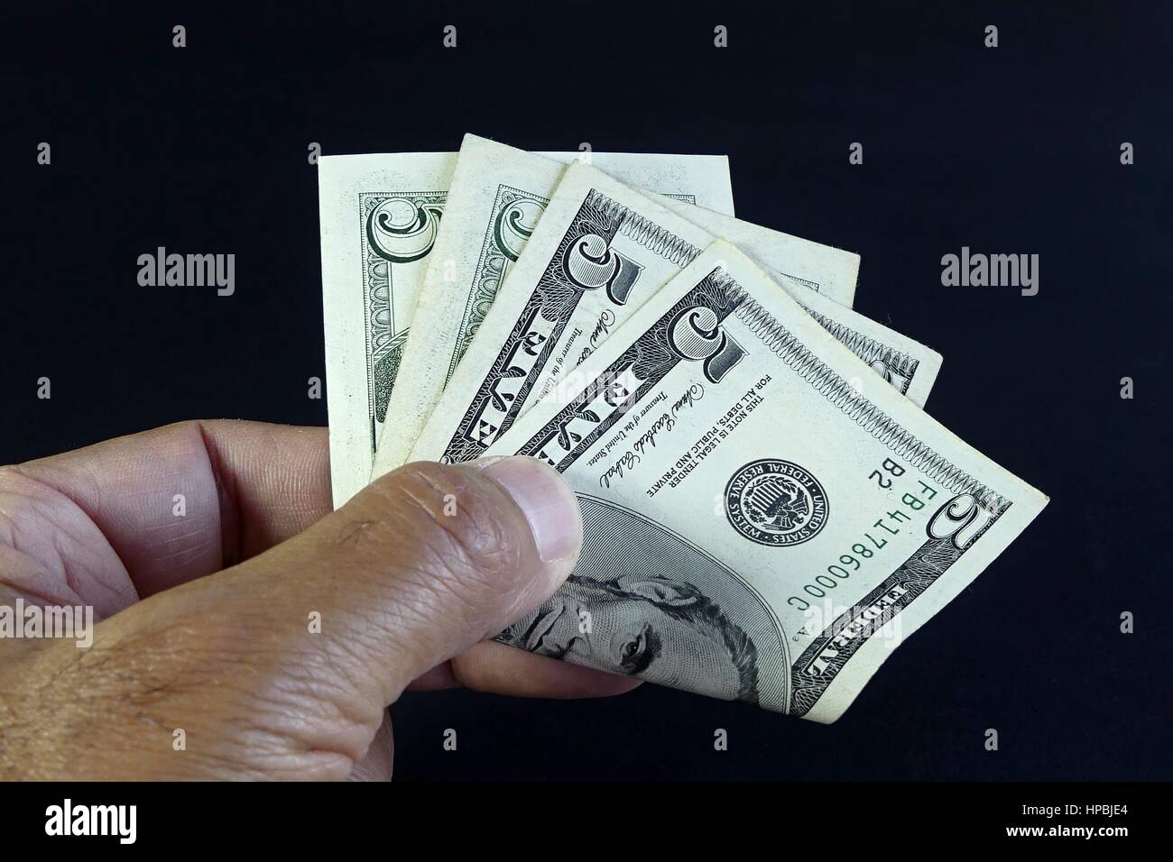 Isolierte Hand des Menschen geben US-Dollar auf schwarzem Hintergrund Stockfoto