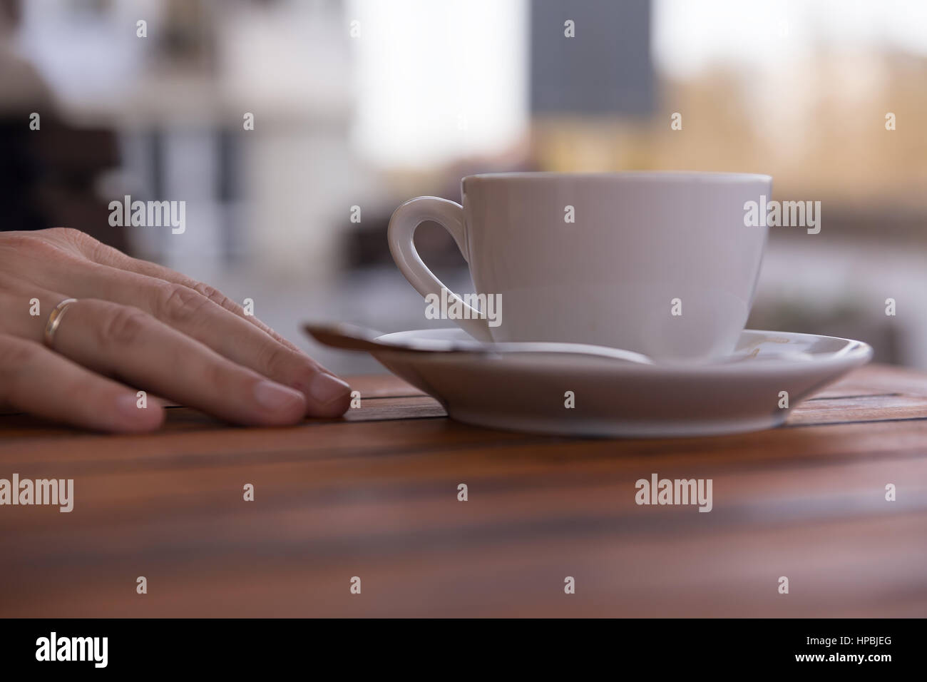 Hand eines jungen Mannes auf einem Holztisch im Café mit Kaffee in Ruhe entspannen Hand Haltung, im freien Hintergrund weichzeichnen Stockfoto