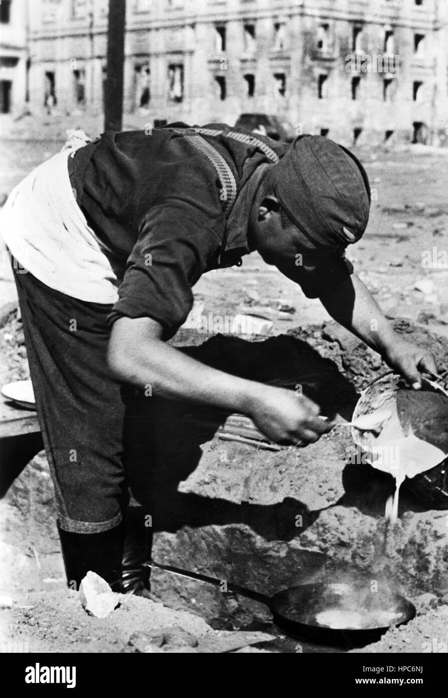 Die Originalfotografie, aus der dieses digitale Bild gemacht wurde, liest auf dem Rücken die nationalsozialistische Propaganda vom 22. Oktober 1942: "Pfannkuchen an einem Bahnhof in Stalingrad. Der Koch einer Flak-Batterie bereitet das Mittagessen zu - heute sind es Pfannkuchen.“ Fotoarchiv für Zeitgeschichte | weltweite Verwendung Stockfoto