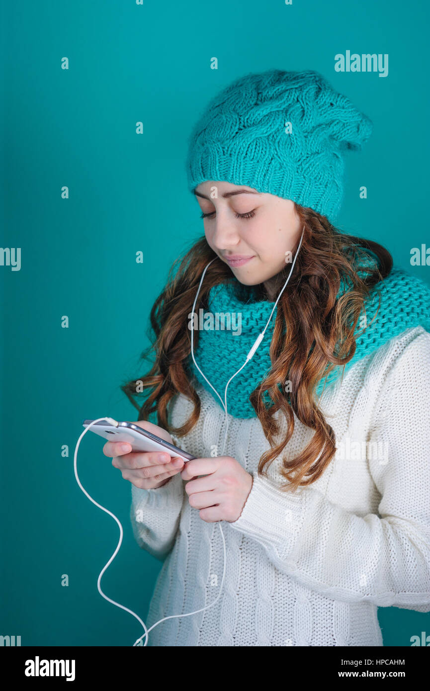 junge Frau mit einem Telefon in der Hand, das Anhören von Musik über Kopfhörer Stockfoto