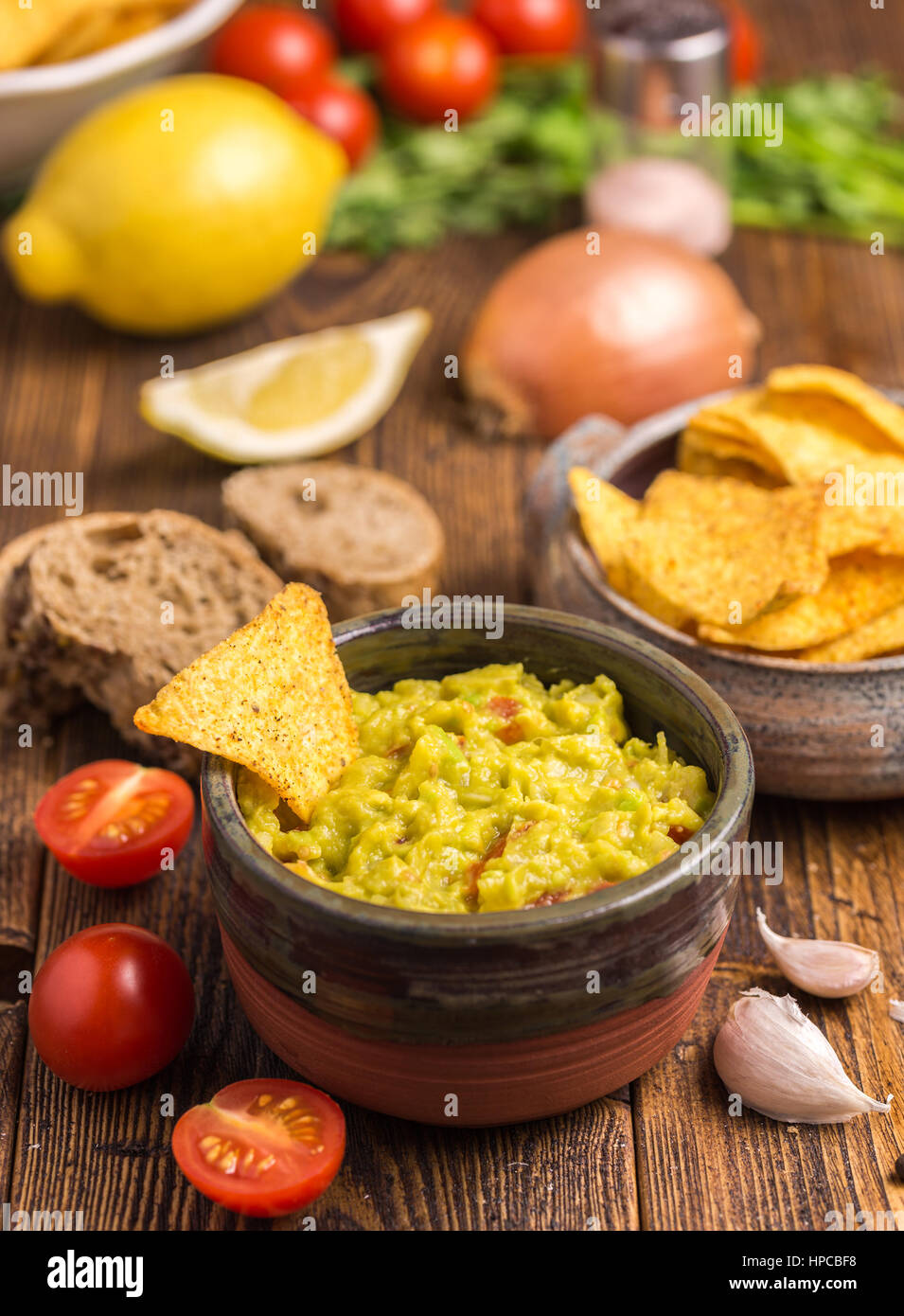 Guacamole in braune Schale mit Tortilla-Chips auf natürlichen hölzernen Schreibtisch. Stockfoto