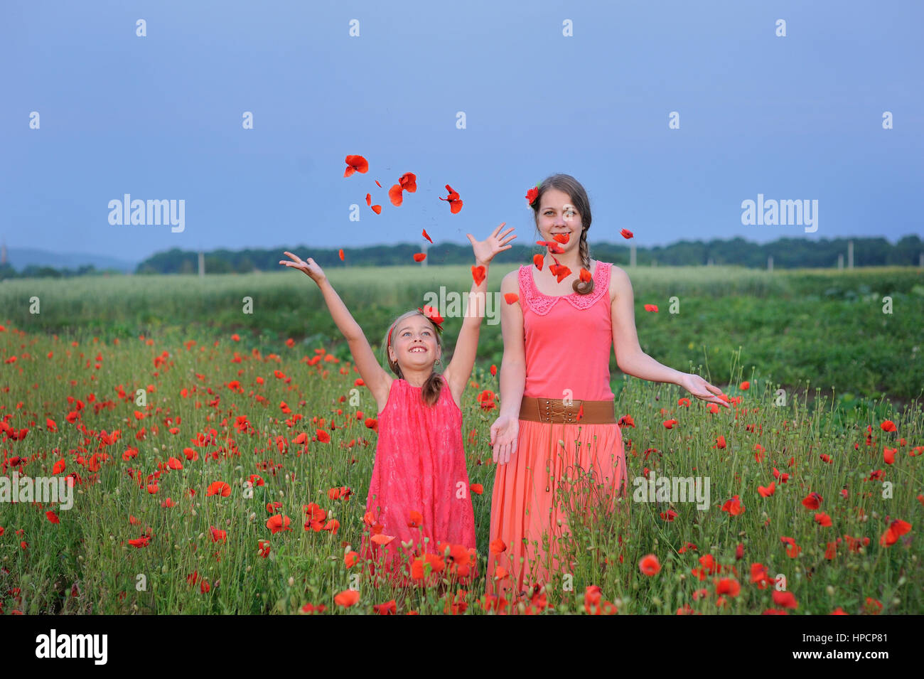 zwei Mädchen in einem roten Kleid zu Fuß auf das Mohnfeld im Frühjahr. Stockfoto