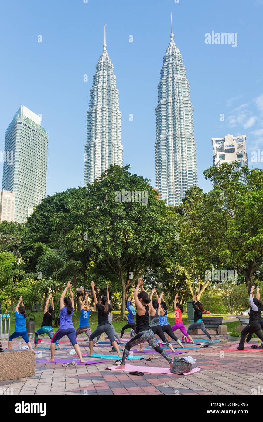 Kuala Lumpur, Malaysia - 24. September 2016: Malaysische Frauen Yoga üben im Park mit Petronas Towers auf Hintergrund in Kuala Lumpur, Malaysia Stockfoto