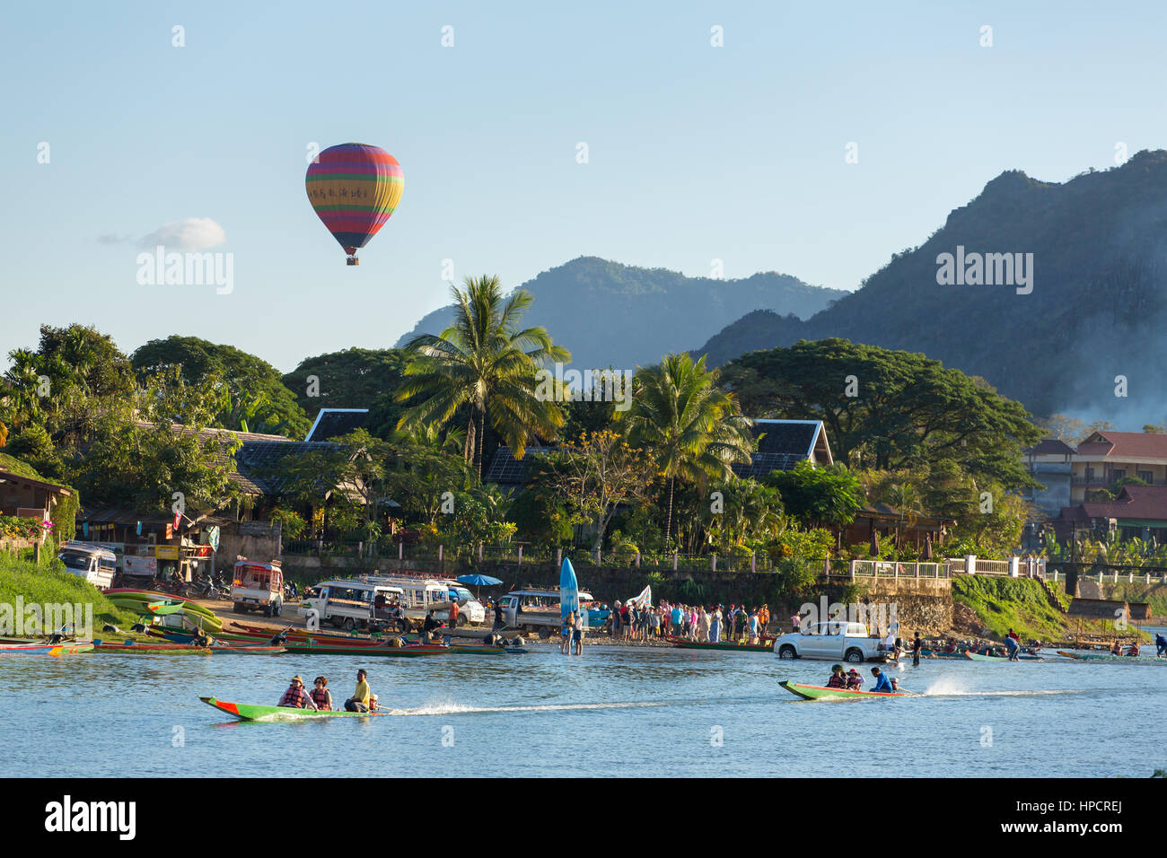 Vang Vieng, Laos - 19. Januar 2017: Unidentified Touristen fahren Schnellboote in Vang Vieng Dorf mit einem Heißluftballon auf Hintergrund. Stockfoto