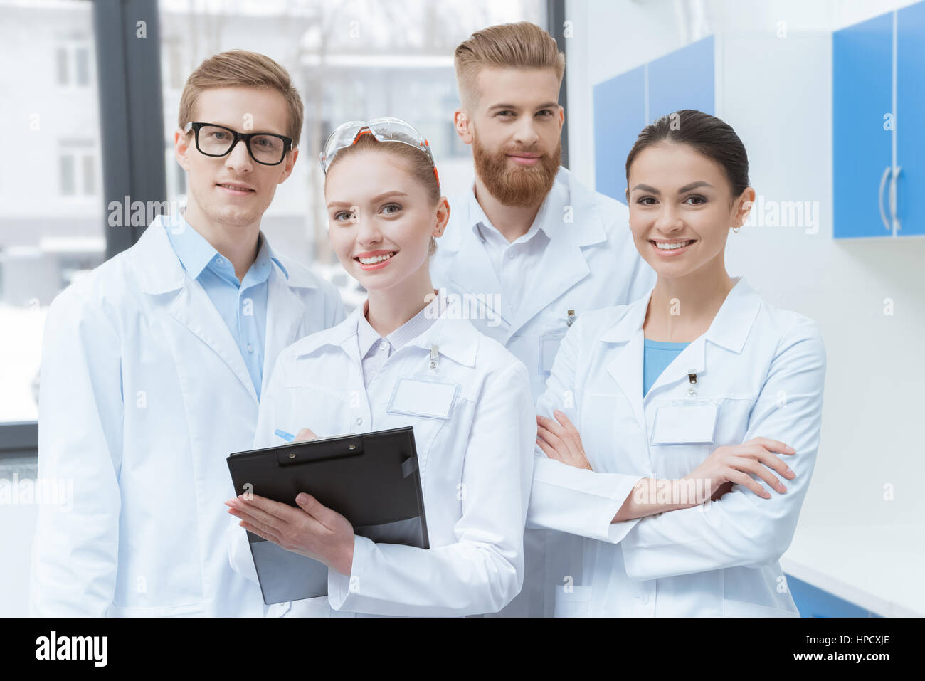 Team von jungen Wissenschaftlern in Laborkitteln lächelnd in die Kamera Stockfoto