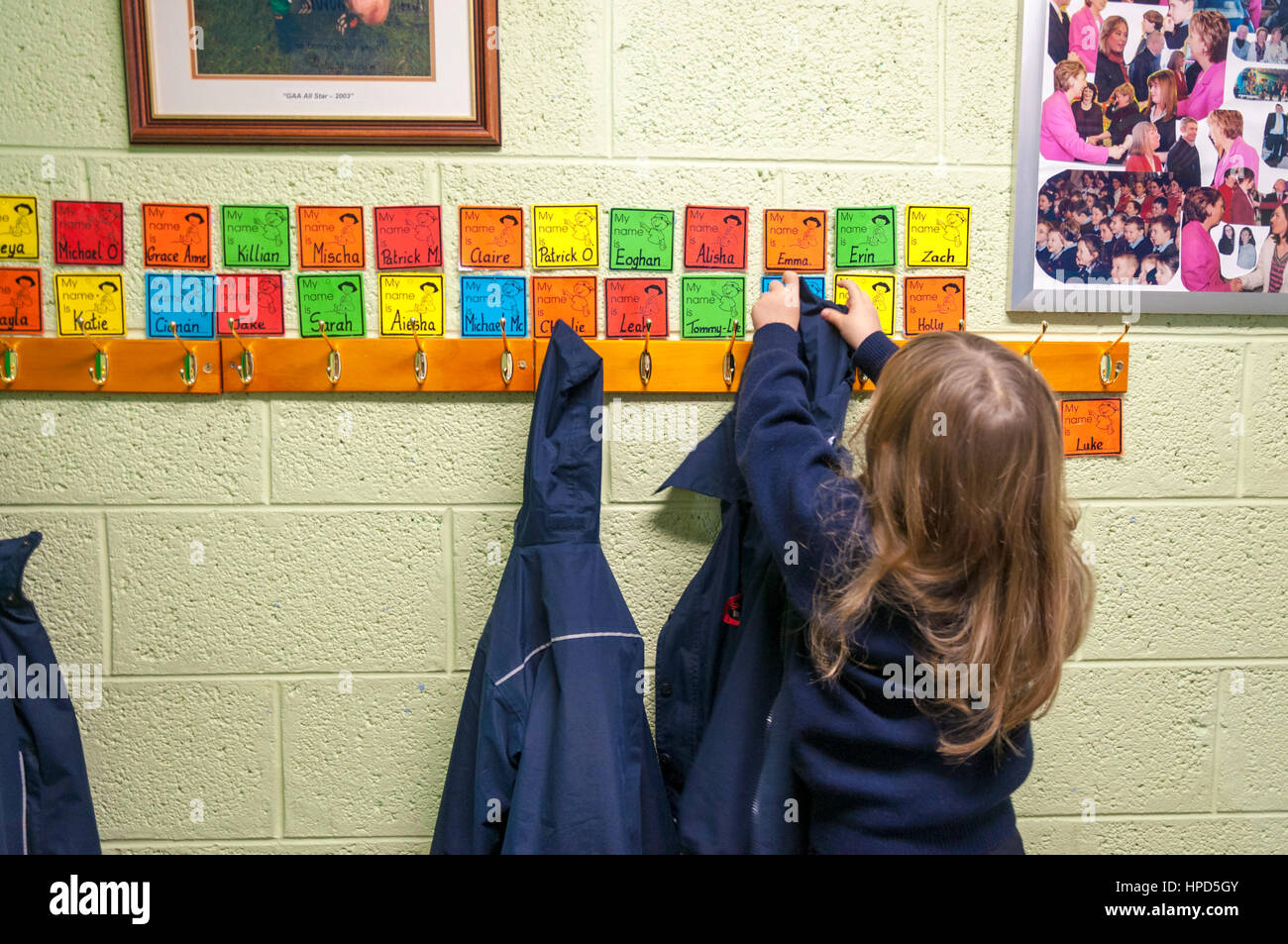 Ein Kind legt auf ihren Mantel auf benannte Kleiderbügeln an einer Schule in County Donegal, Irland Stockfoto