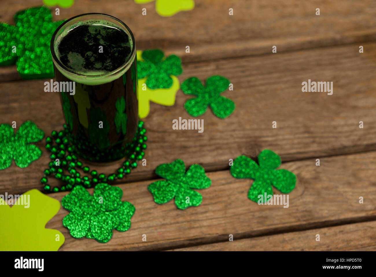 Glas Jungbier, Perlen und Shamrock für St. Patricks Day auf Holztisch Stockfoto