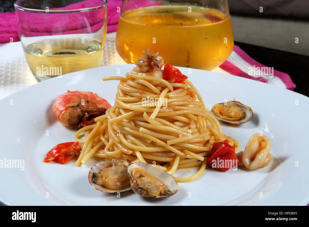 Pasta mit Meeresfrüchten in weißen Schale auf bunte Küchentücher und kühlen Weißwein (Glas und Karaffe) im Hintergrund. Italienische Spaghetti allo Scoglio Rezept Stockfoto