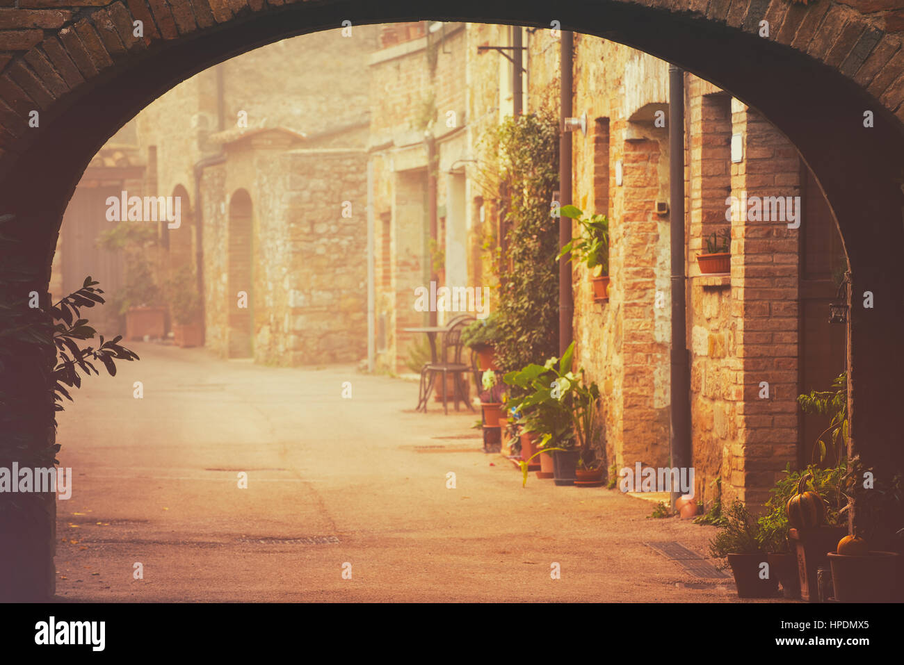 Gasse der Altstadt San Quirico d ' Orcia mit Bogen, Grünpflanzen und Kopfsteinpflaster, Reisen, nebligen Morgen Italien Hintergrund. Vintage Hipster sty Stockfoto