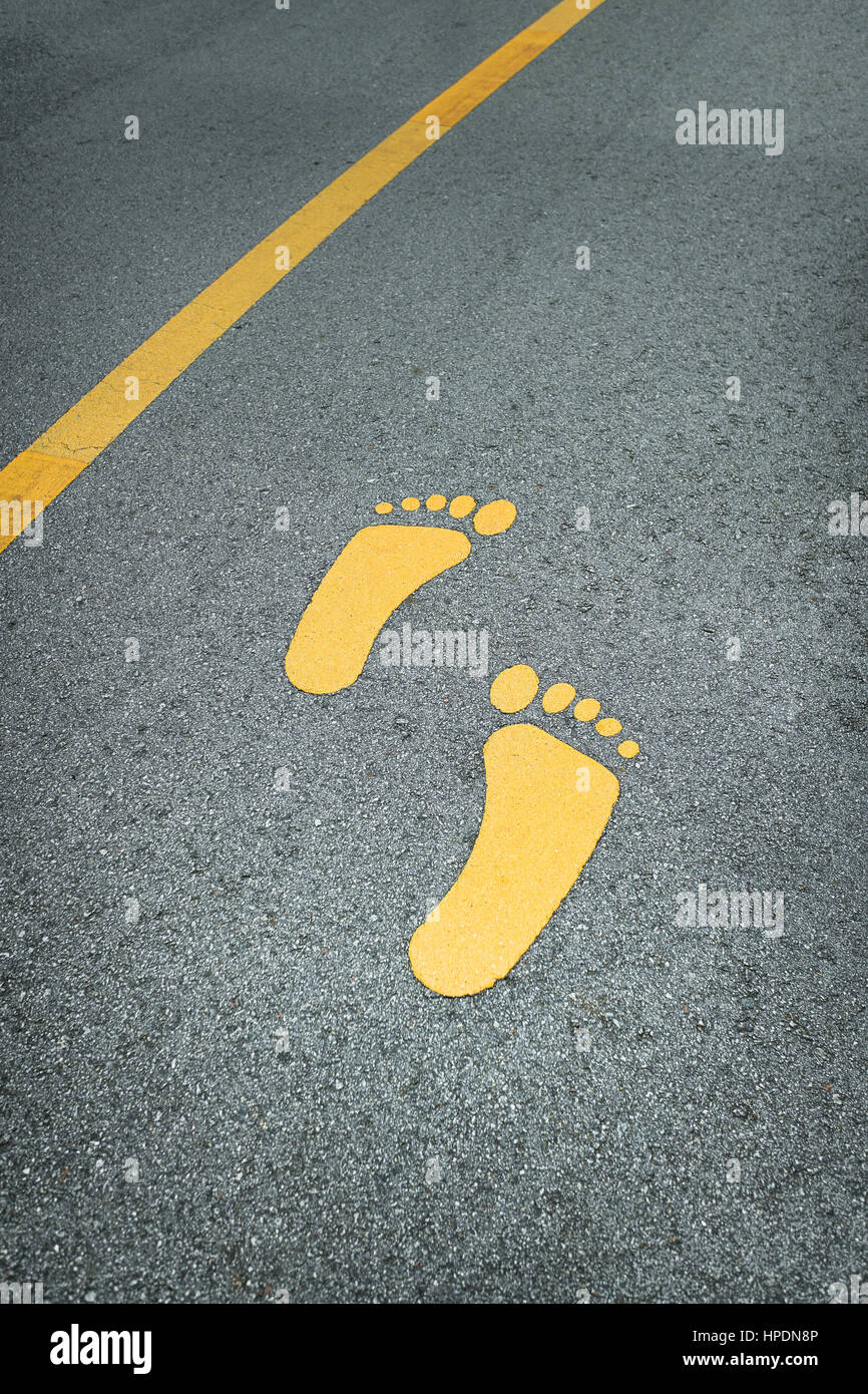 Fuß-Zeichen auf der Asphaltstraße und gelbe Linie Stockfoto