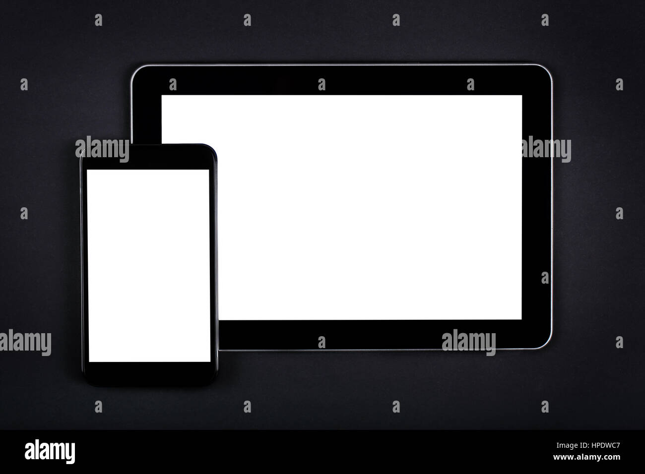 Moderne generische Tablet und Smartphone mit leere Bildschirme auf schwarzen Tisch. Stockfoto