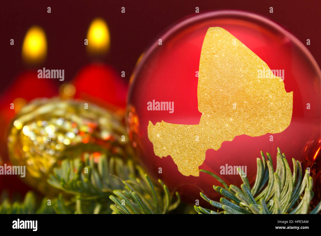 Eine glänzende rote Christbaumkugel mit der goldenen Form von Mali. (Serie) Stockfoto