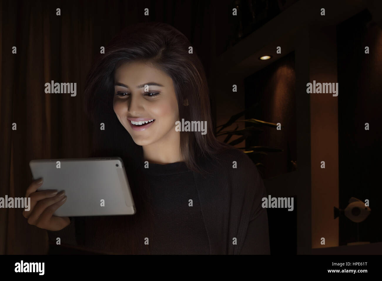 Lächelnde Frau mit digital-Tablette in einem dunklen Raum Stockfoto
