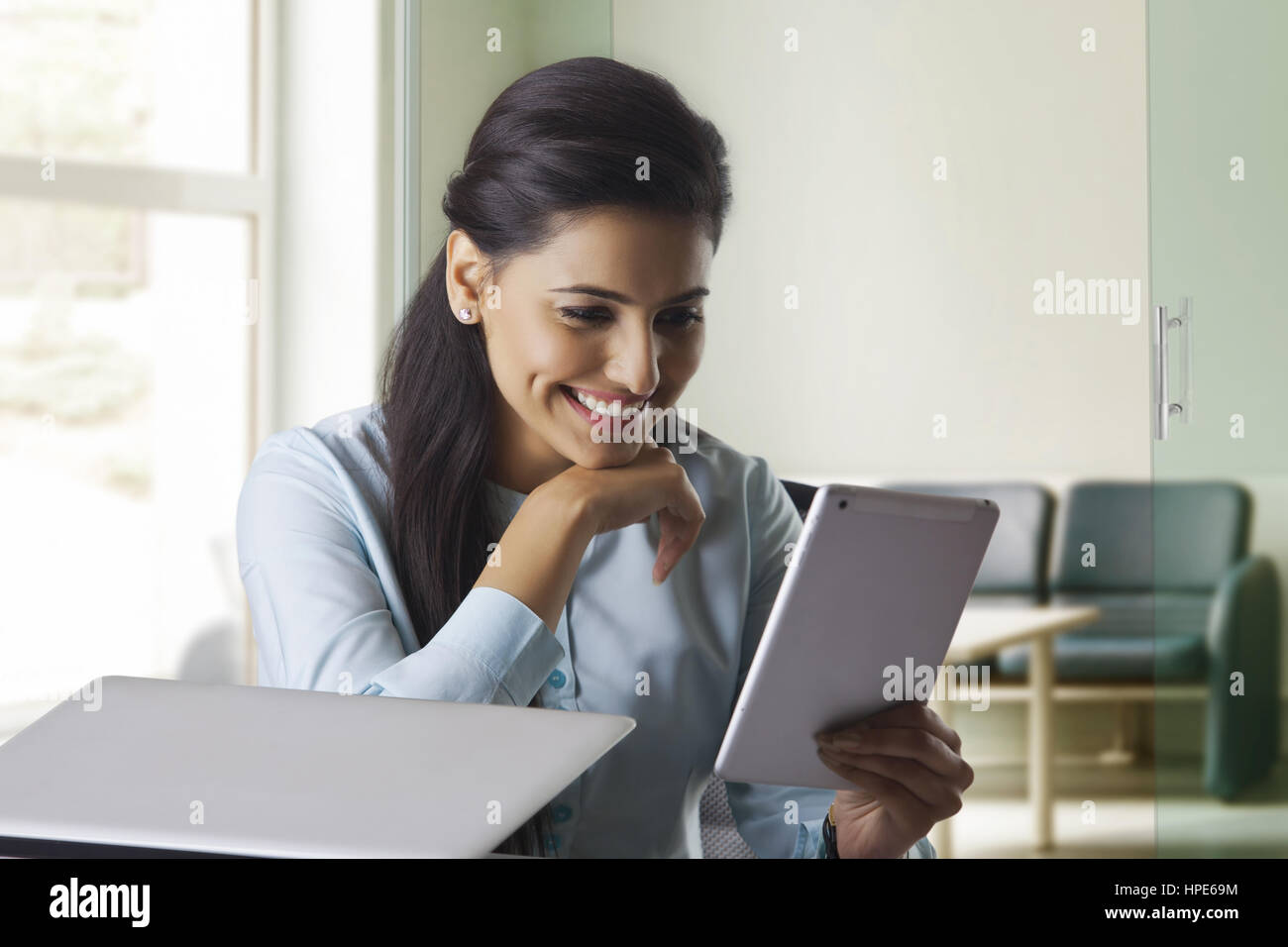 Lächelnde Geschäftsfrau mit digital-Tablette im Büro am Schreibtisch Stockfoto
