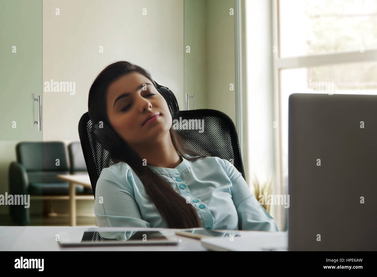 Entspannte Geschäftsfrau Musik hören im Büro Stockfoto