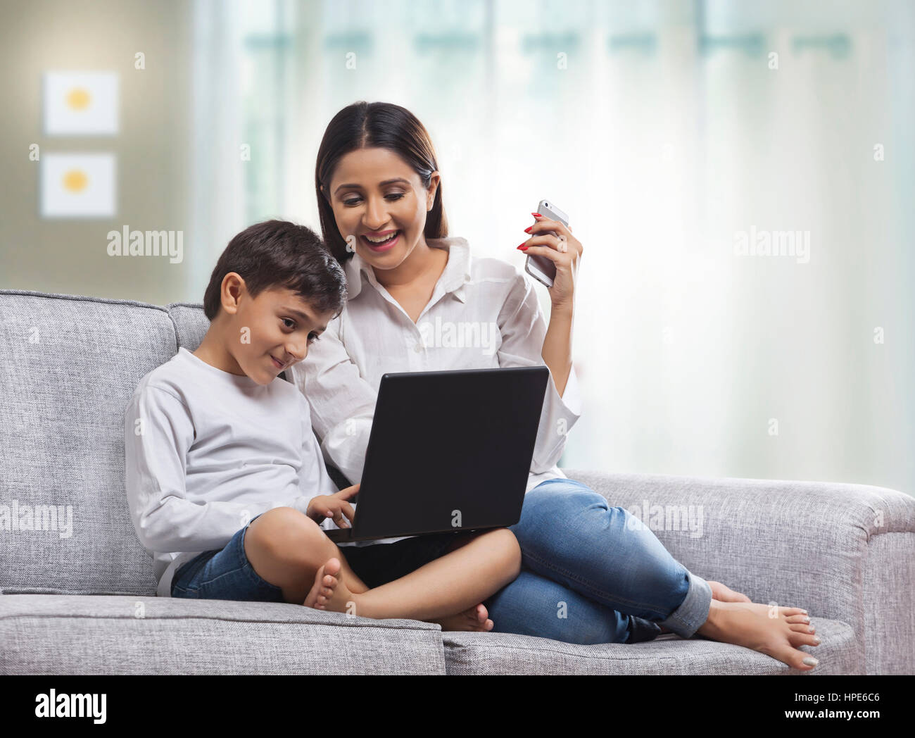 Mutter und Sohn mit Laptop im Wohnzimmer Stockfoto