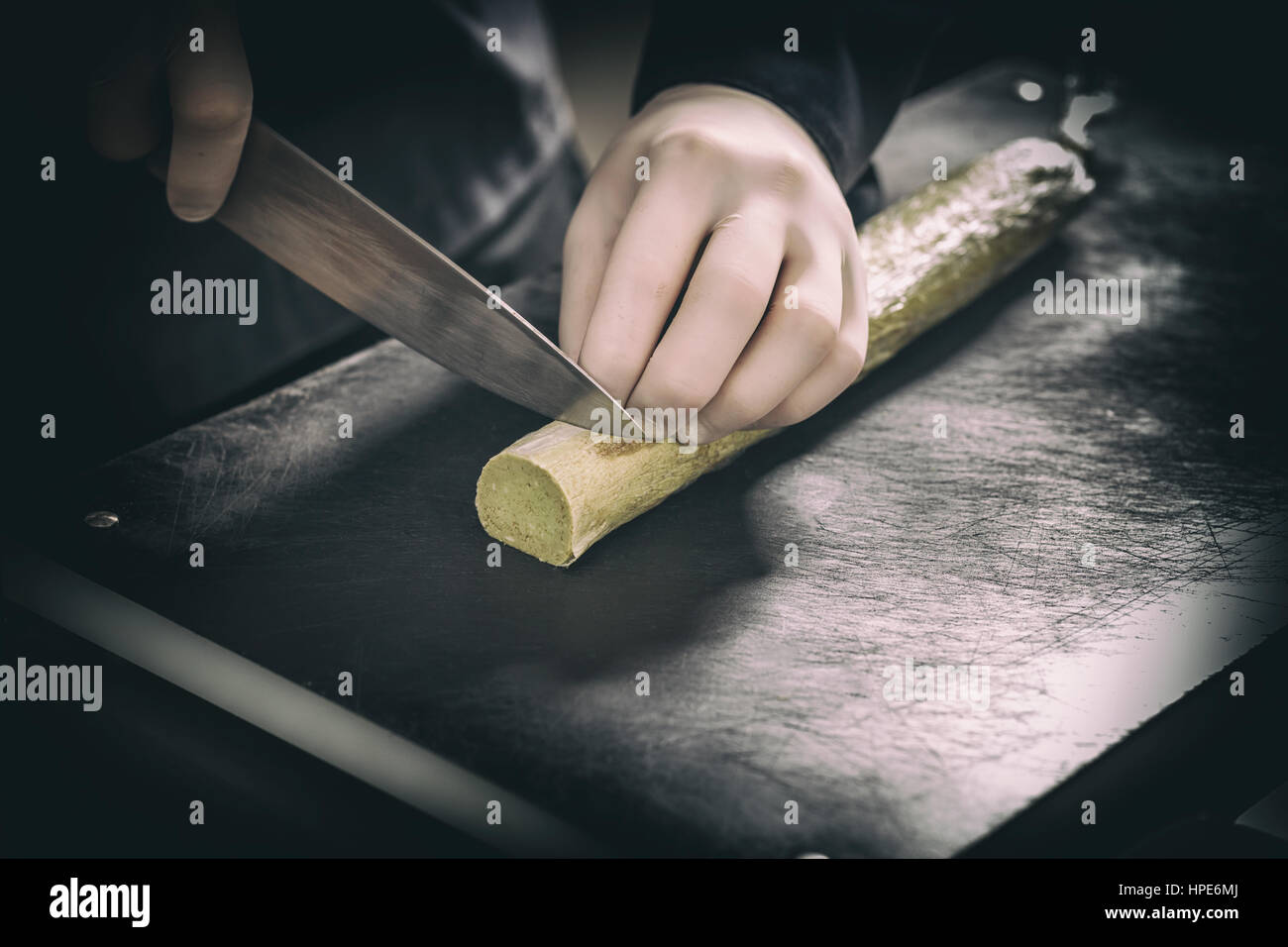 Koch schneiden zusammengesetzte Butter auf schwarze Schneidebrett Stockfoto