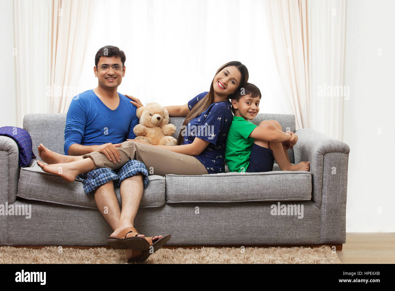 Porträt von lächelnden jungen Eltern mit ihrem Sohn auf dem Sofa sitzen Stockfoto
