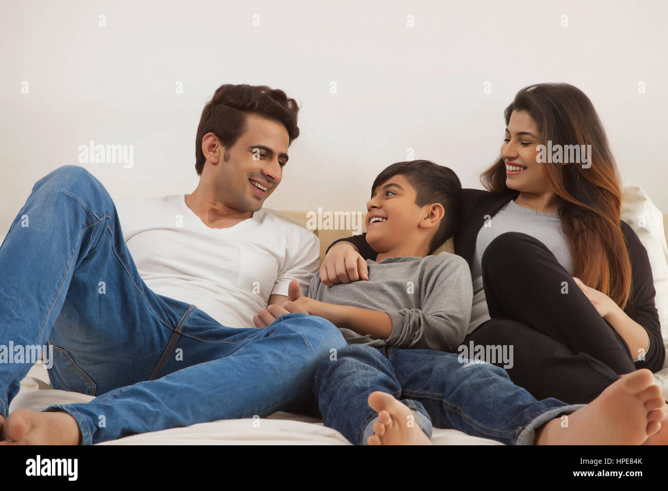 Lächelnden Eltern mit Sohn im Bett entspannen Stockfoto