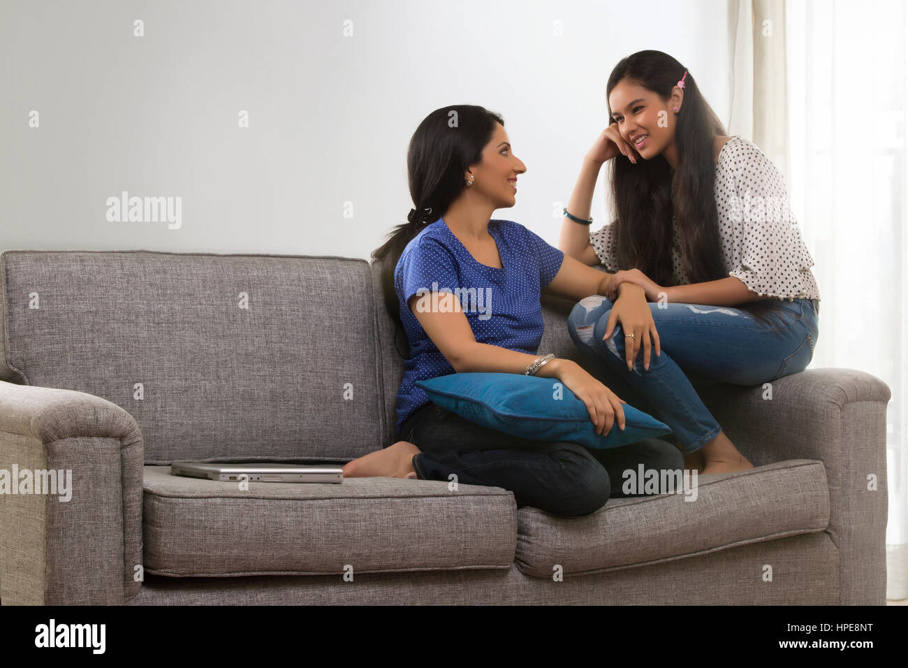 Lächelnde Mutter und Tochter sitzen im Wohnzimmer Stockfoto