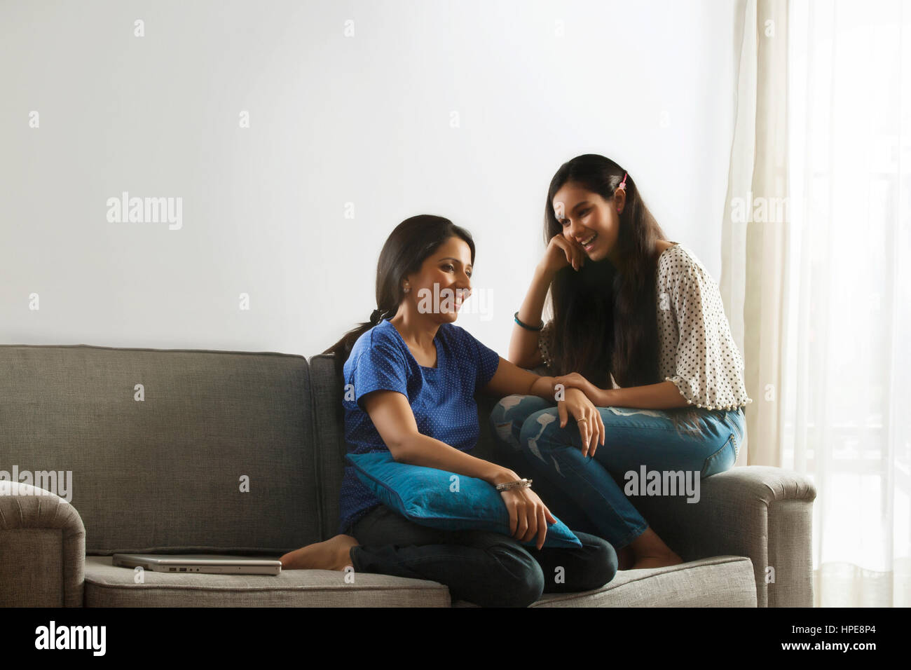 Mutter im Gespräch mit ihrer Tochter im Teenageralter auf Sofa im Wohnzimmer Stockfoto