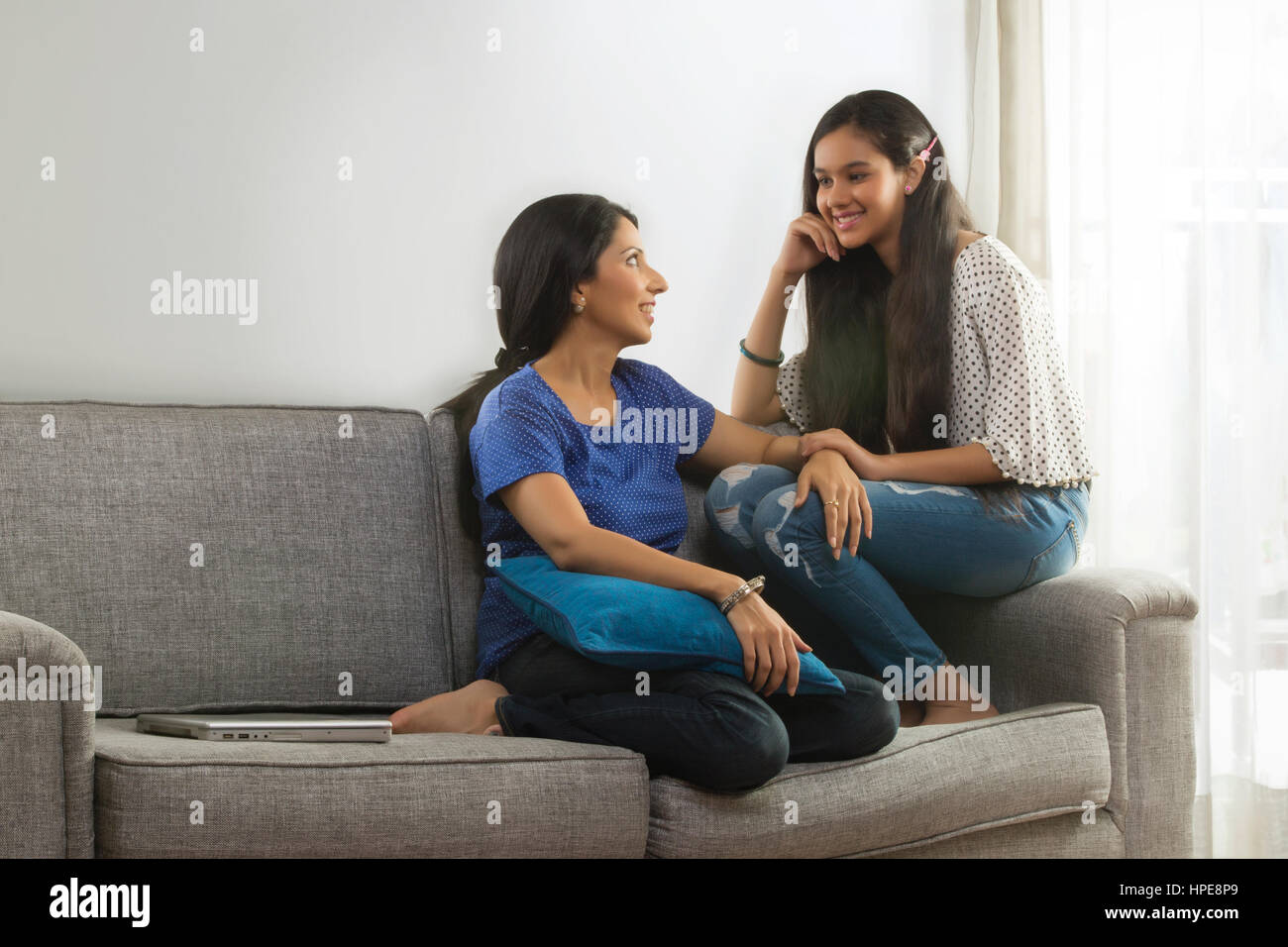 Mutter im Gespräch mit ihrer Tochter sitzt auf dem Sofa im Wohnzimmer Stockfoto