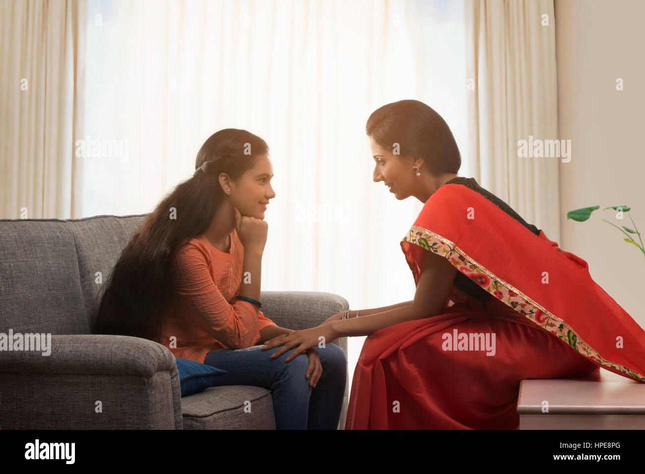 Mutter in einem roten Sari im Gespräch mit ihrer Tochter Stockfoto