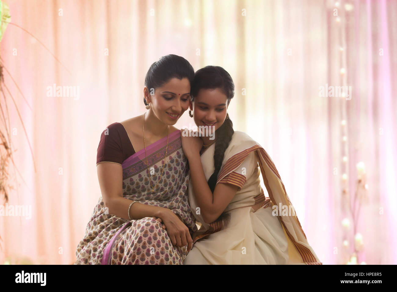 Teenager-Mädchen in Sari sitzt mit ihrer Mutter lächelnd Stockfoto