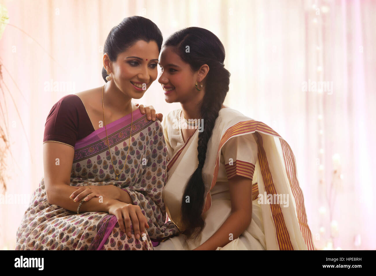 Teenager-Mädchen in Sari flüsterte Mutter lächelnd Stockfoto