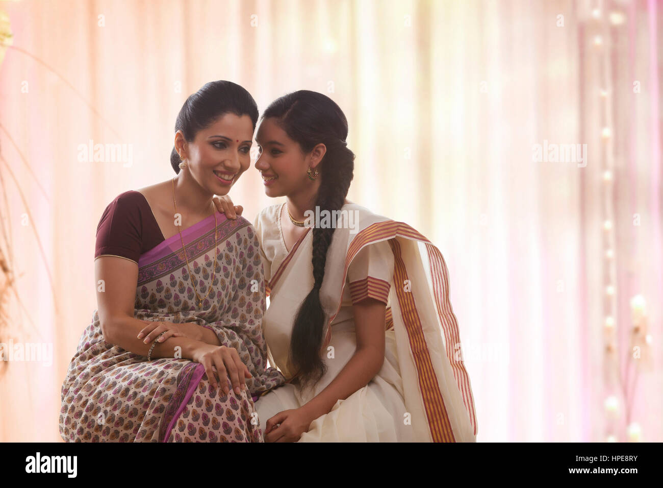 Teenager-Tochter in Sari flüsterte Mutter lächelnd Stockfoto