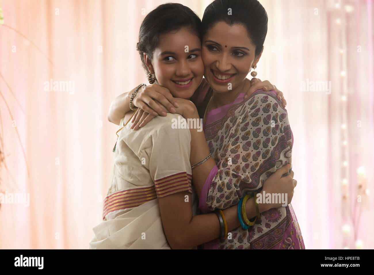 Lächelnde Teenager-Tochter in Sari und Mutter umarmt Stockfoto