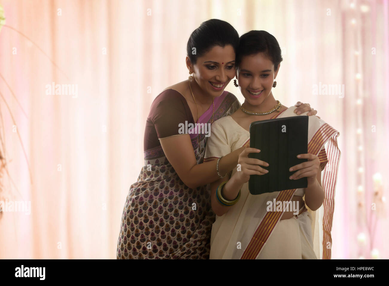 Lächelndes Mädchen in Sari mit einem digital-Tablette mit Mutter Stockfoto