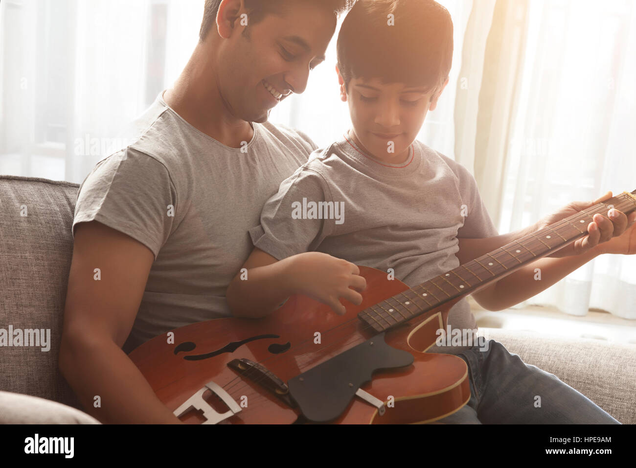 Junge von seinem Vater Gitarrespielen lernen Stockfoto