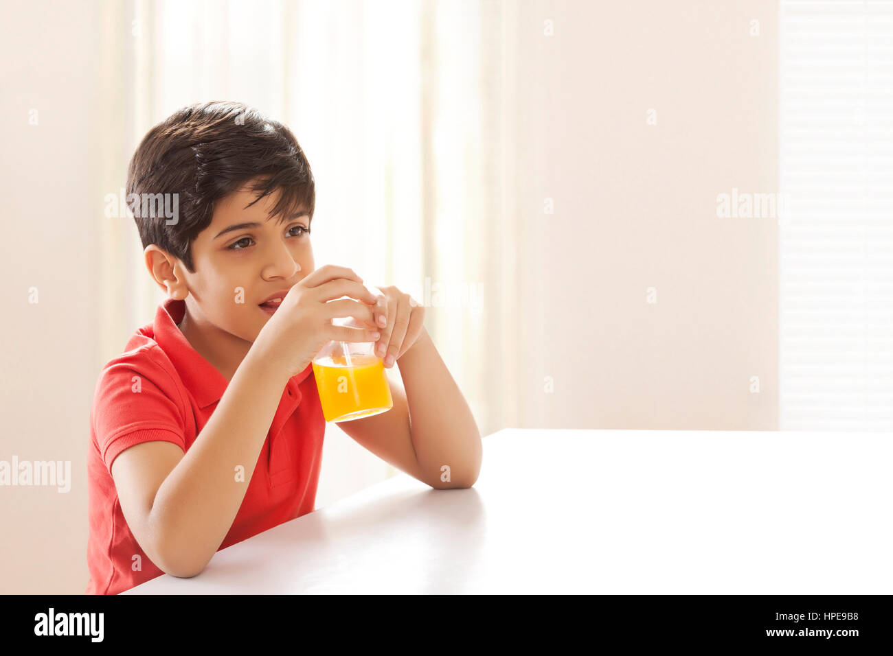 Junge Saft am Esstisch sitzen zu trinken Stockfoto