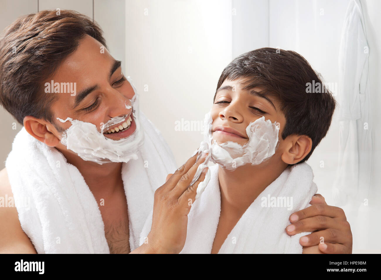 Mann Anwendung Rasierschaum Seifenschaum auf Gesicht seines Sohnes während der Rasur Bart Stockfoto
