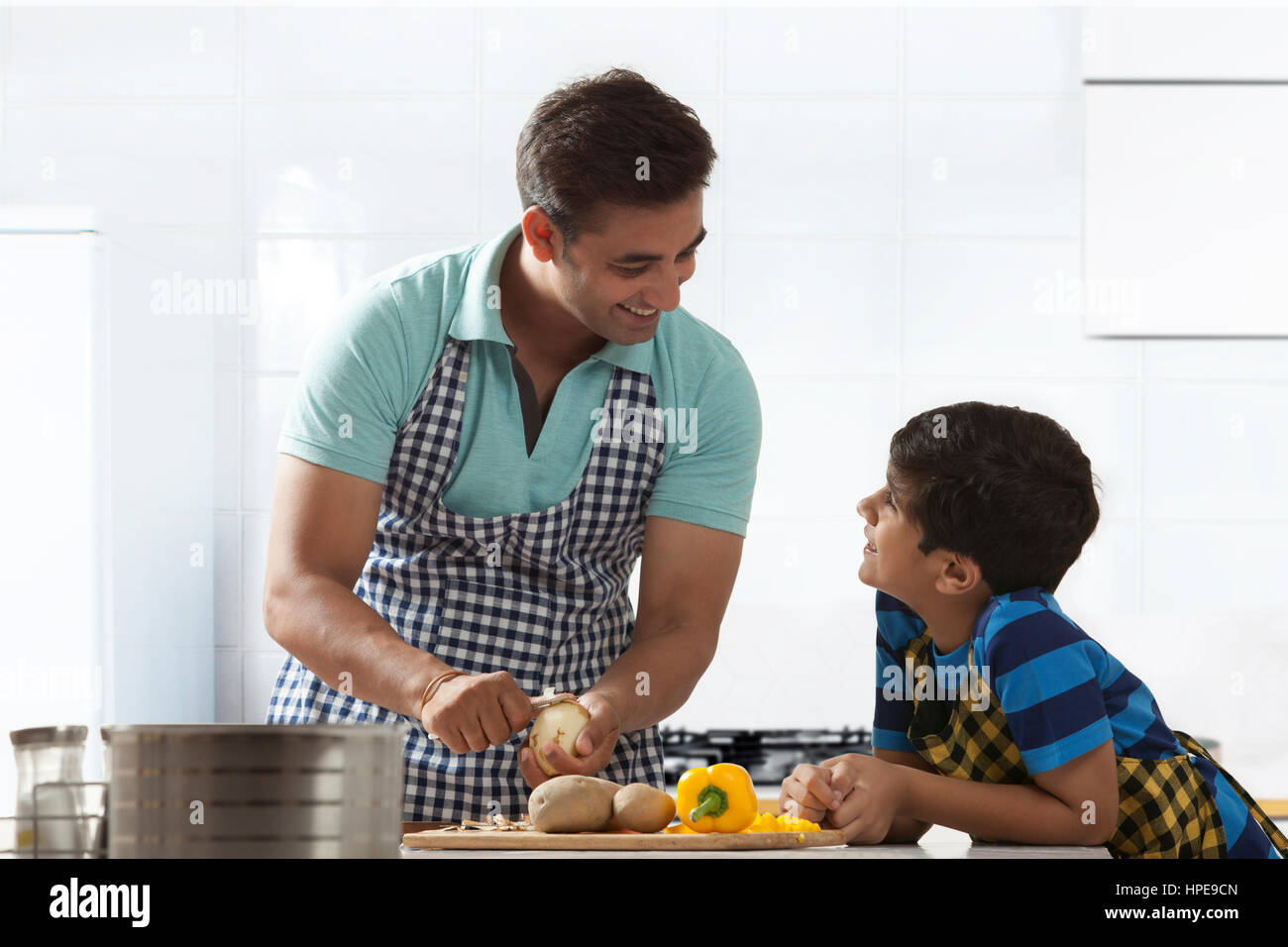 Kartoffelschälen in Küche, während im Gespräch mit seinem Sohn Vater Stockfoto