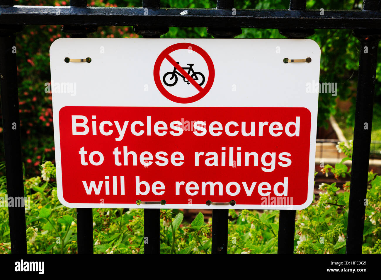 Zeichen, die Warnung, dass Fahrräder dazu gesichert Geländer werden auf einem Zaun Geländer entfernt. UK Stockfoto