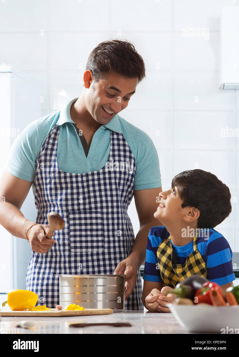 Vater und Sohn Kochen und schmecken Suppe in Küche Stockfoto