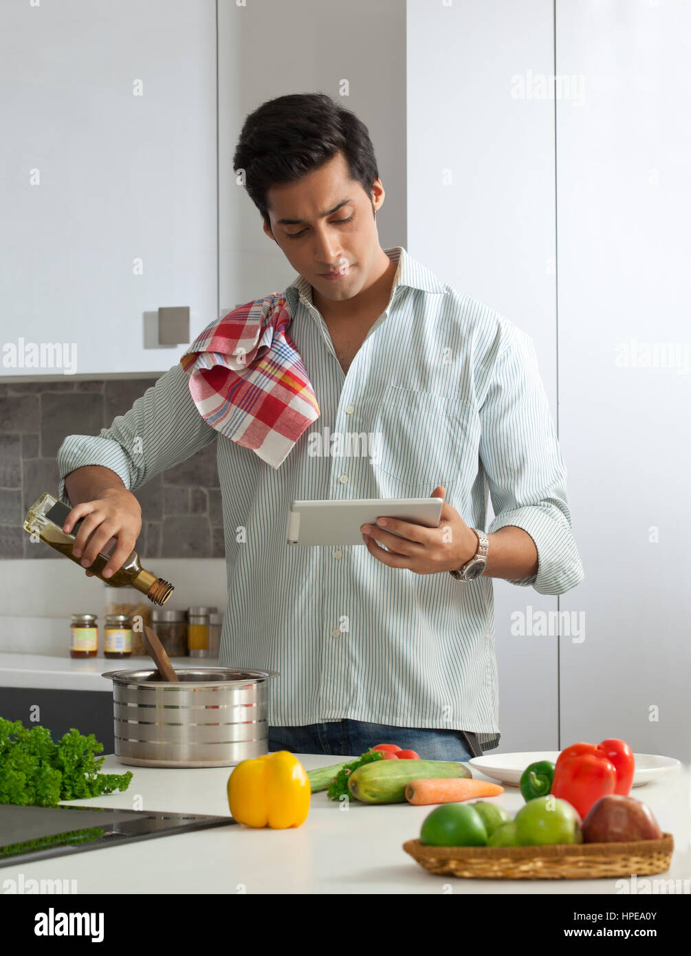 Mann, Kochen, mit einem digitalen Tablet für Rezepte Stockfoto