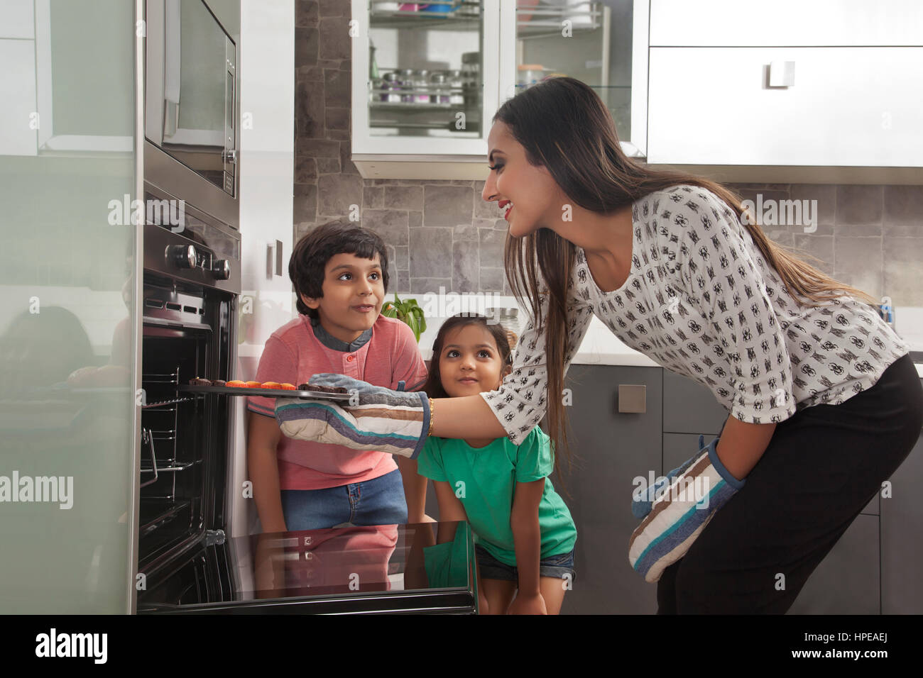 Mutter mit ihren zwei Kindern backen im Ofen Stockfoto