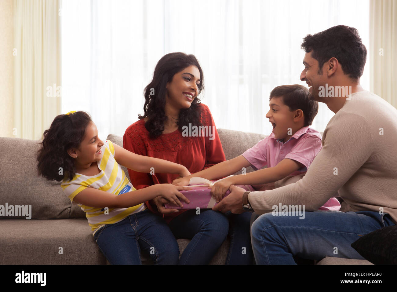 Glückliche Familie von vier reißt eine Geschenk-box Stockfoto