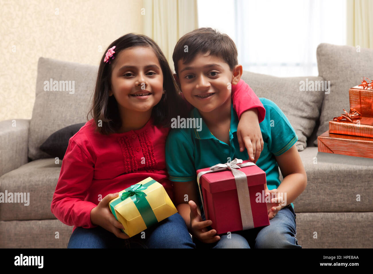 Jungen und Mädchen holding präsentiert sitzen zusammen im Wohnzimmer Stockfoto