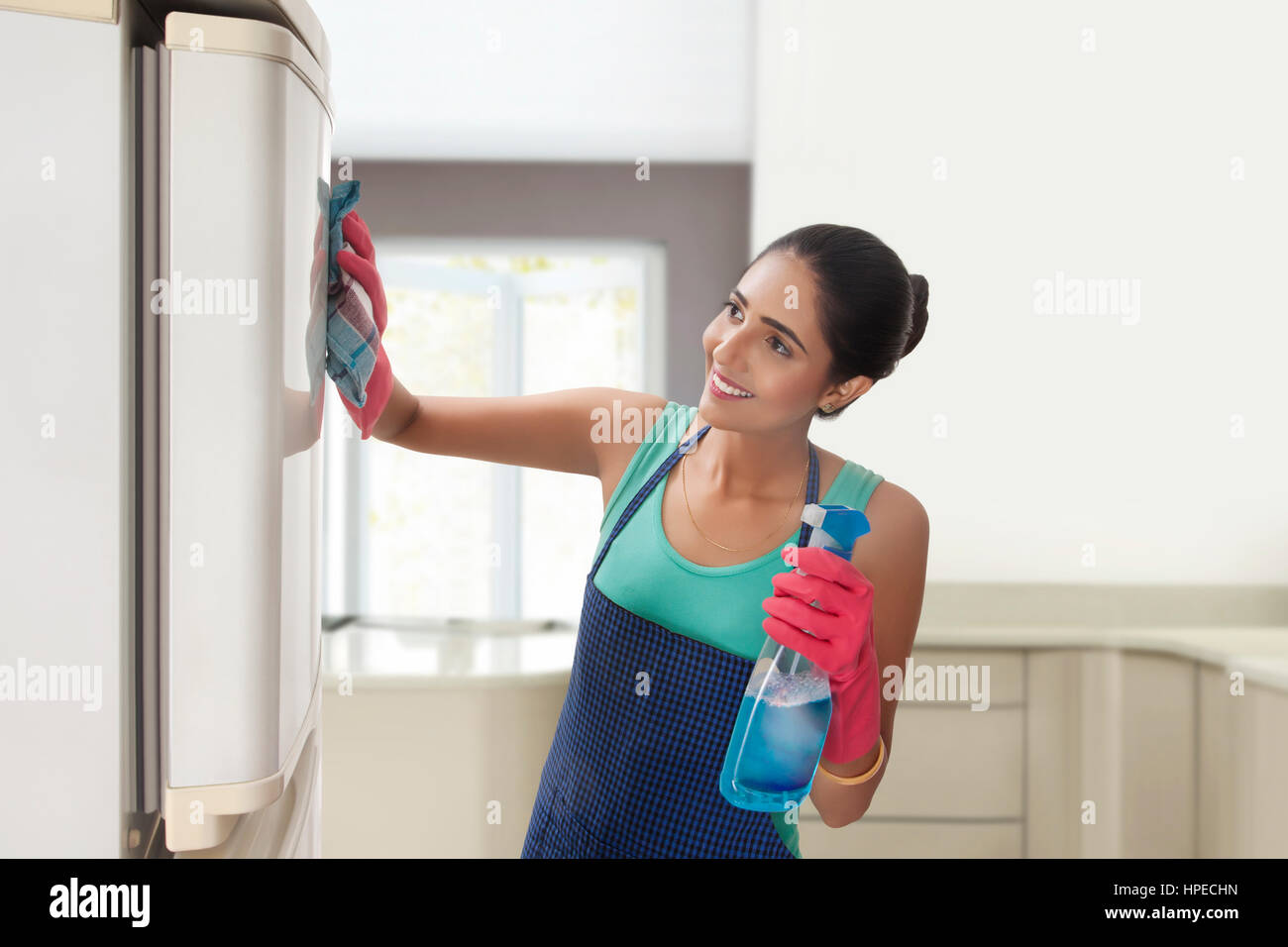 Junge Frau Kühlschrank mit Spray Reiniger Reinigung Stockfoto