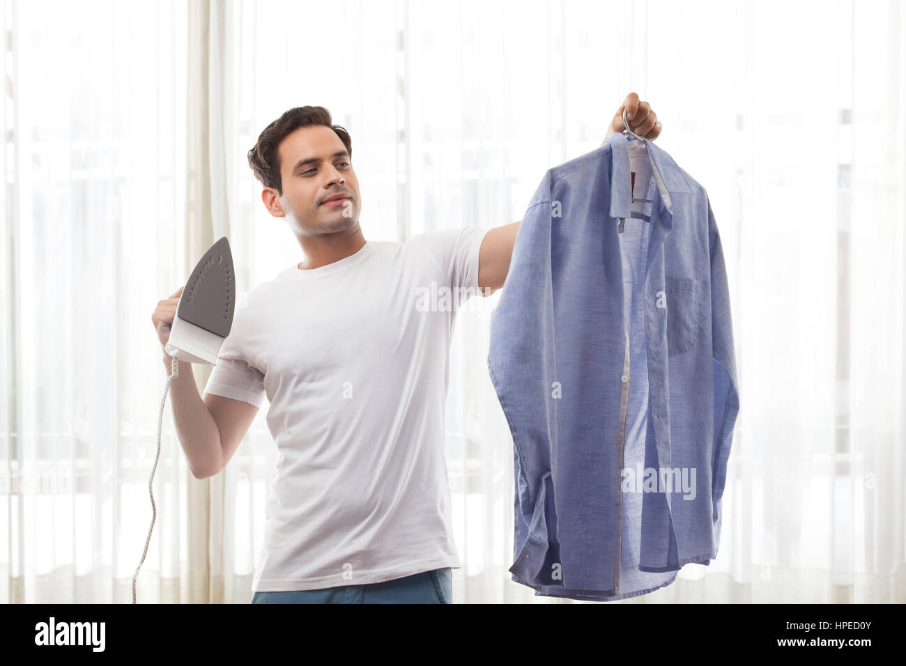 Junger Mann sein Hemd Bügeln Stockfoto