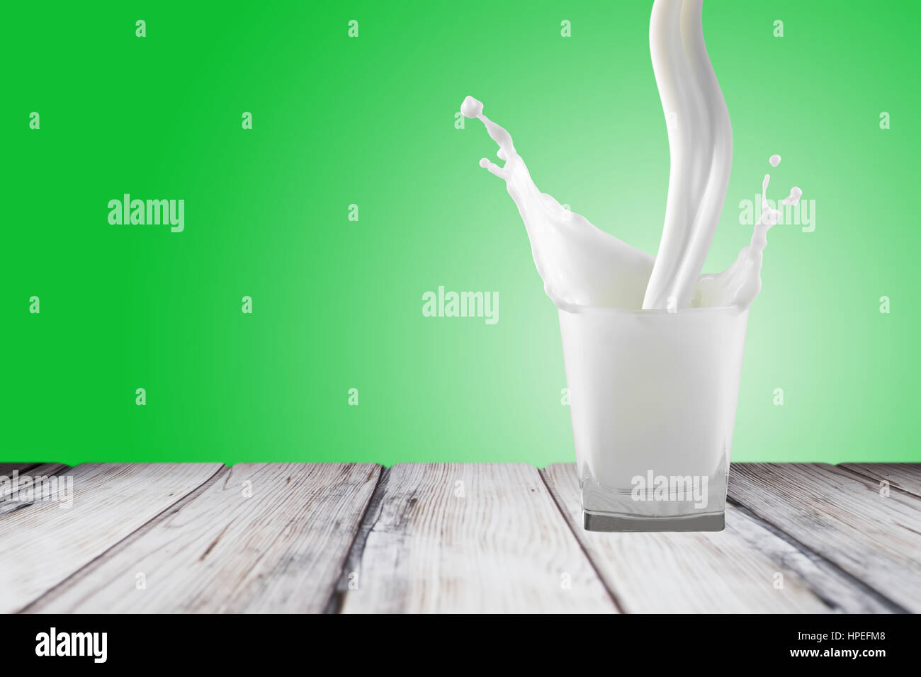 Milch Spritzen im Glas isoliert grün Hintergrund Stockfoto