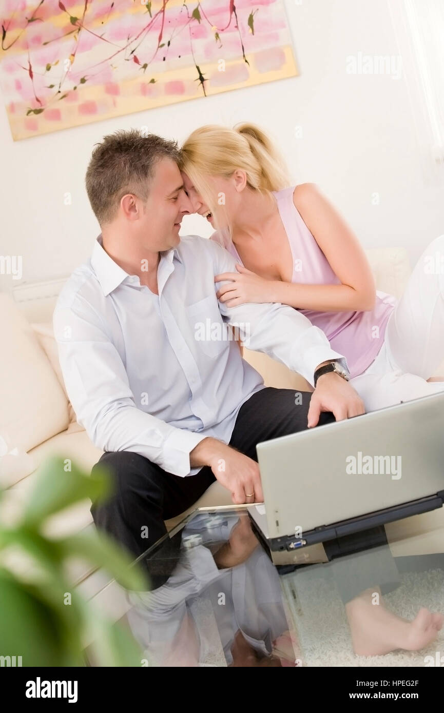 Model Release, Lachendes Paar Sitzt Mit Laptop Auf Couch Im Wohnraum - glückliche Paar mit laptop Stockfoto