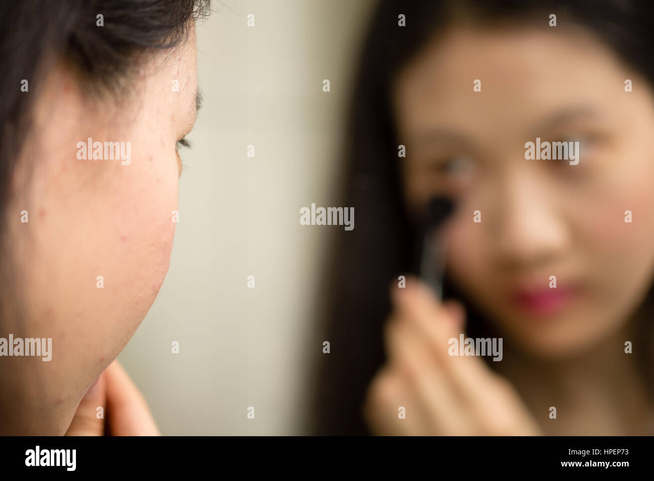 Chinesische Jugendliche setzen auf Make-up mit Pinsel vor Spiegel Stockfoto