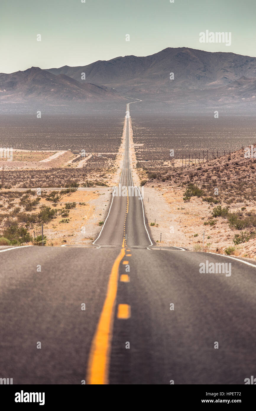 Klassische Ansicht einer endlosen geraden Straße laufen durch die karge Landschaft des amerikanischen Südwestens mit extremer Hitze Dunst an einem schönen sonnigen Tag Stockfoto Klassische Ansicht einer endlosen geraden Straße laufen durch die karge Landschaft des amerikanischen Südwestens mit extremer Hitze Dunst an einem schönen sonnigen Tag Stockfoto
