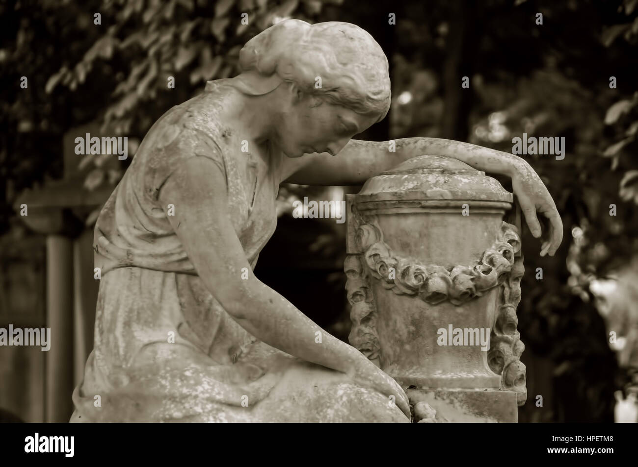 Weibliche Figur gebildet vom Stein, beugte sich über eine Urne auf einem Friedhof, Stockfoto